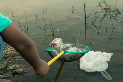 Midsection of woman holding umbrella by lake