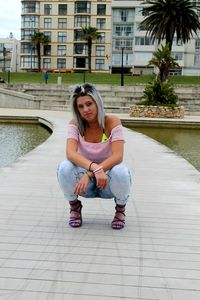 Portrait of woman sitting on footpath in city