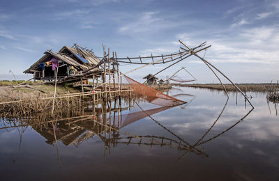 Traditional windmill in lake against sky
