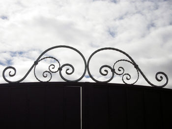 Low angle view of metal fence against sky