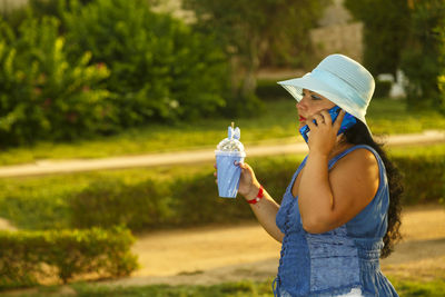 Side view of woman drinking water while standing outdoors