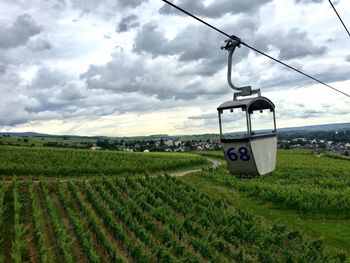 Overhead cable car on agricultural field against sky