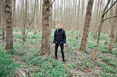 Full length of woman standing on field against trees at forest