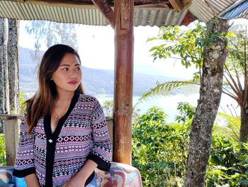 Portrait of beautiful young woman sitting on tree trunk