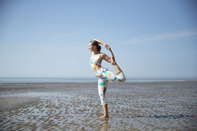 Woman exercising at beach against sky