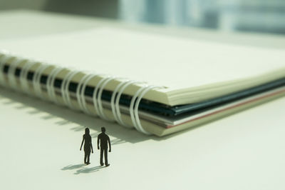 Close-up of figurines with spiral notebooks at desk