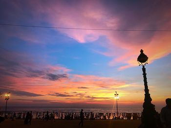 Silhouette people on beach against sky during sunset