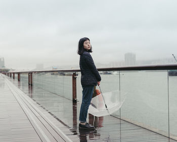 Portrait of woman holding umbrella and standing at riverbank