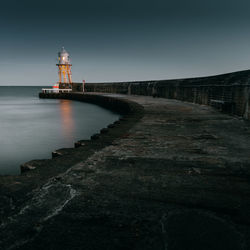 Lighthouse amidst buildings against clear sky