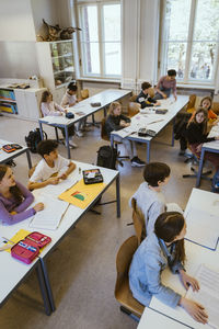 High angle view of male and female students attending lecture sitting in classroom