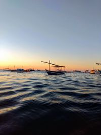 Fishing boats on sea against sky during sunset