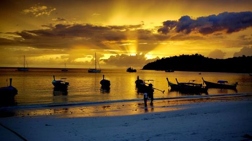 Silhouette people on beach against sky during sunset