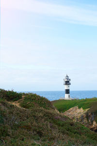 Lighthouse by sea against sky