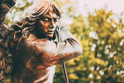 Close-up of young woman statue against plants