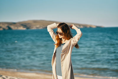 Woman standing at beach against sky