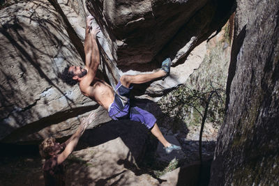 Shirtless man climbing rock