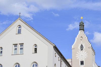 Low angle view of cross amidst buildings against sky