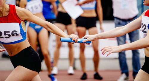 Women relay team passing of baton running 4x400 meters