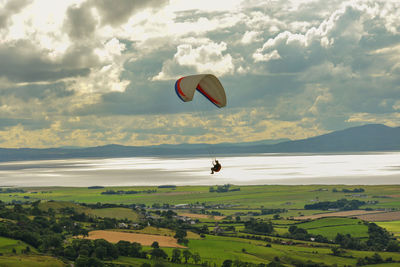 Hot air balloon flying over field against sky