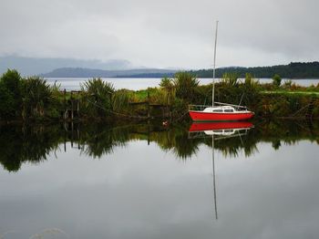 Boat moored in lake against sky