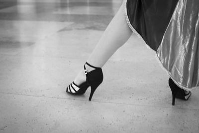 Low section of woman in high heels dancing on tiled floor