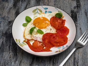 Breakfast with scrambled eggs and fresh tomatoes on a colored plate