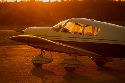 Airplane on airport runway against sky during sunset