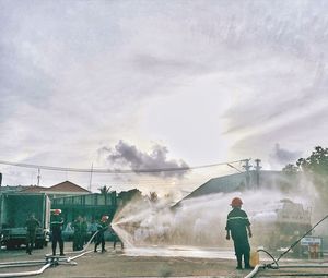 Rear view of people standing on shore against sky