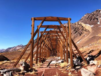 Abandoned railway bridge on land against clear blue sky