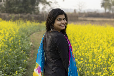 Portrait of smiling young woman standing on field