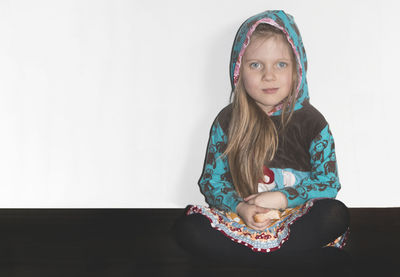 Full length portrait of girl sitting floor against white background