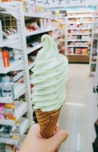 Close-up of hand holding ice cream cone at store