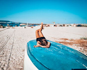 Woman relaxing on beach against blue sky