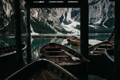 Boats moored in lake against mountains during winter