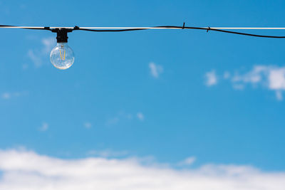 Vintage light bulb with blue sky and white clouds on background. electricity concept. earth hour.