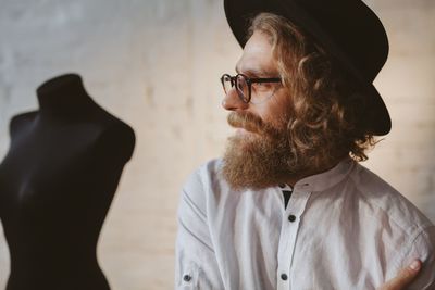 Fashion designer looking away against mannequin