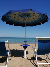 Chairs on beach by sea against sky