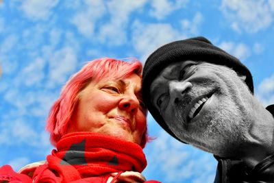 Smiling couple looking away against blue sky