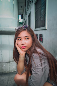 Young woman looking away while crouching in city