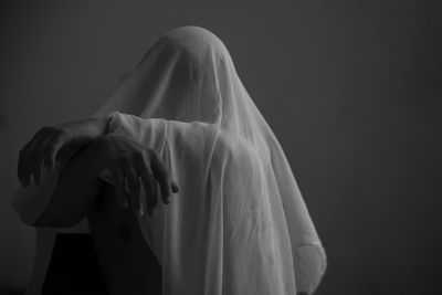 Person covered with fabric sitting on chair