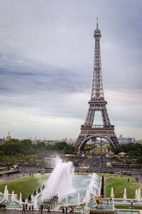 Eiffel tower on paris with a gray sky and a fountain in front