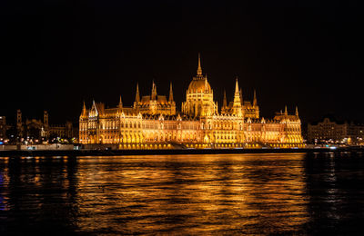 Illuminated hungarian parliament building by danube river