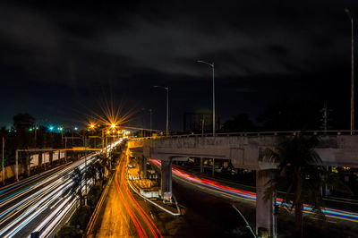 Light trails on street against sky at night