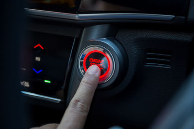Close-up of human hand pushing button in car