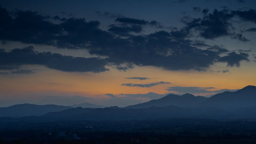 Scenic view of silhouette mountains against dramatic sky during sunset