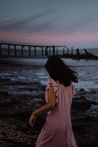 Woman standing on beach against sky during sunset