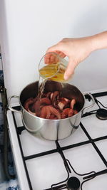 Cropped hand preparing octopus in utensil on stove