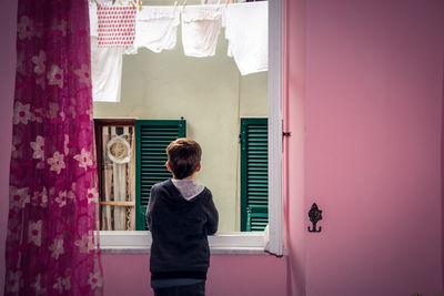 Rear view of boy standing against window