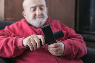 Senior man holding remote controls