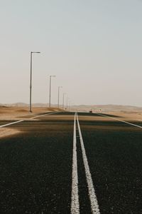 Empty, sandy road on field against clear sky